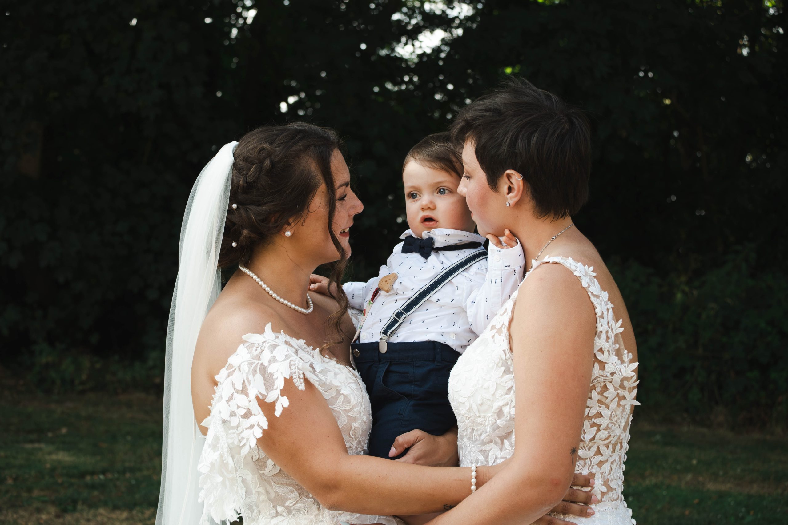 Photo de famille spontanée des deux mariées avec leur enfant le jour de leur mariage.