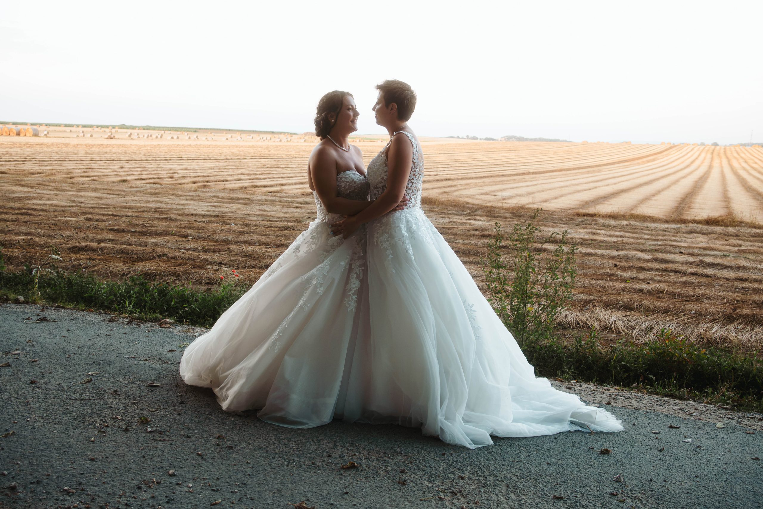 Deux mariées enlacées lors d'une séance photo de couple le jour de leur mariage en Normandie.